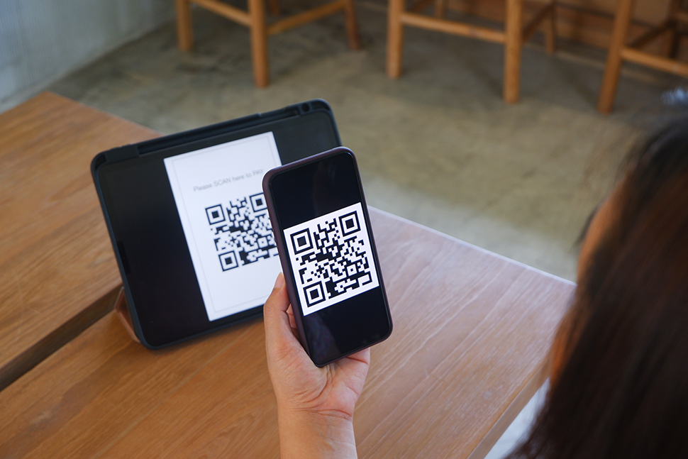 Women's hand uses a mobile phone application to scan QR codes in stores that accept digital payments