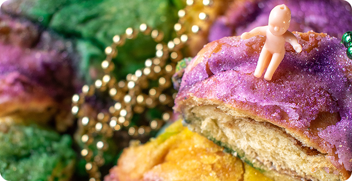 King cake with baby surrounded by mardi gras beads