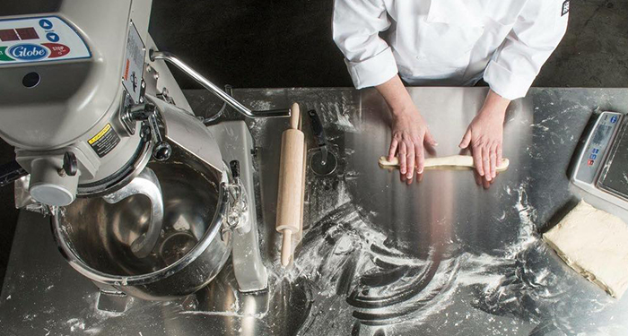 Chef rolling dough from a planetary mixer