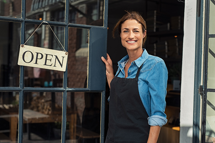 Woman hold open entrance to small business 
