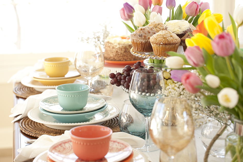 Table setting with tulips, wine glasses and pastel dinnerware.