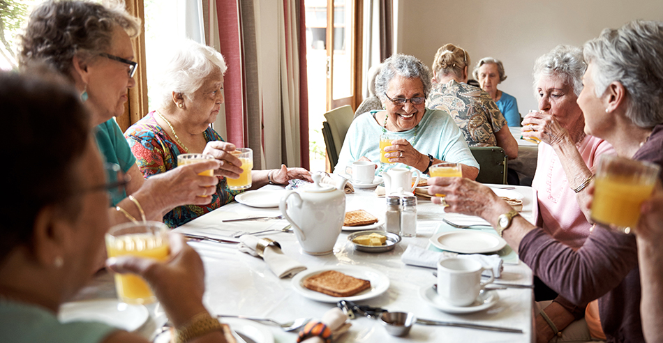 Seniors eating and drinking around a table