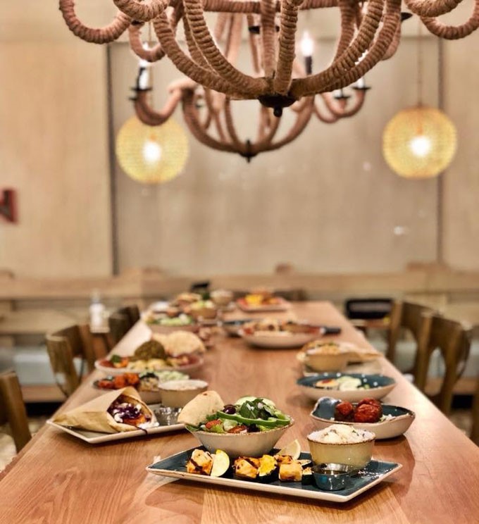 Interior at Zoës Kitchen, Family-style wood table and a variety of Mediterranean dishes