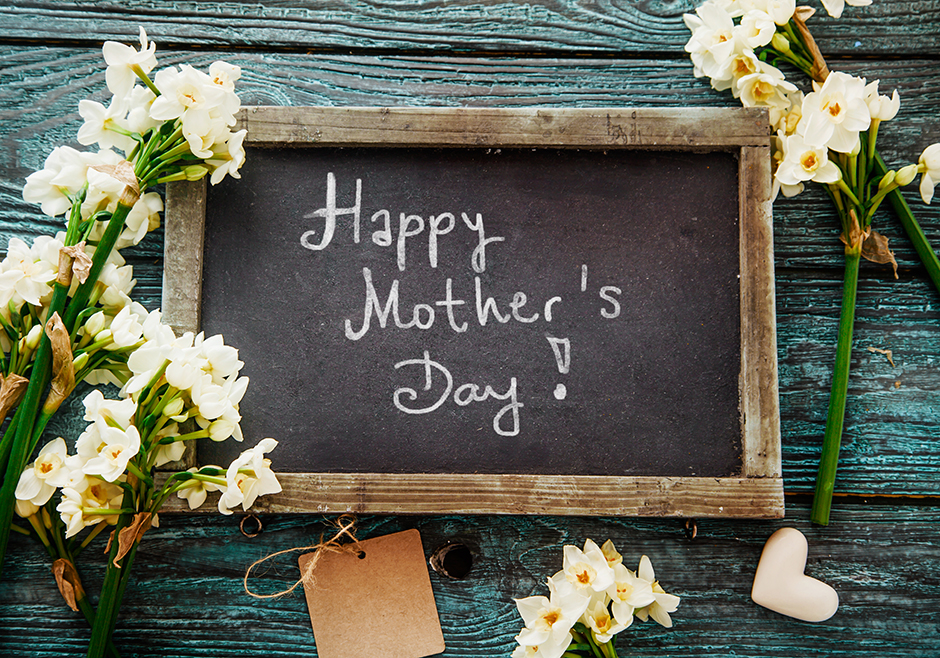 Happy Mother’s Day! Written in white chalk on black board with flowers around