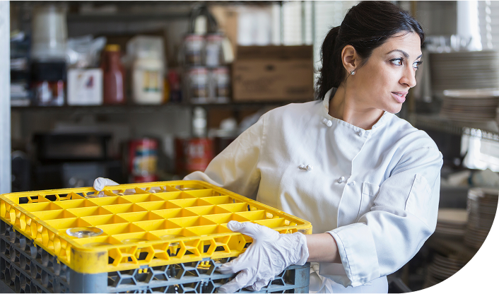 Commercial dish washer employee moving crates of dishes